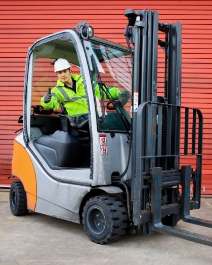 Man operating a forklift, giving a thumbs up